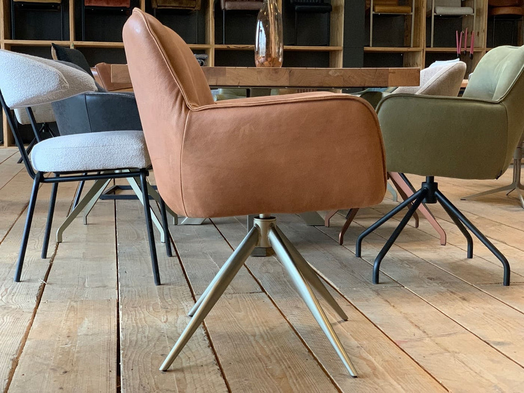 Seitenansicht eines modernen Armlehnenstuhls aus hochwertigem Leder in edlem Cognac, drehbar und mit schlankem Metallgestell – eleganter Sitzkomfort für stilvolle Wohn- und Arbeitsbereiche.