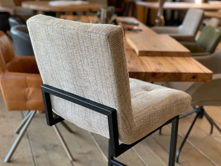 Barhocker Stoffbezug Industrial Detail: Nahaufnahme der Rückenlehne mit hellgrauem Stoffbezug und feiner Struktur, kombiniert mit einem schwarzen Metallrahmen im Industrial-Stil, die die hochwertige Verarbeitung hervorhebt.