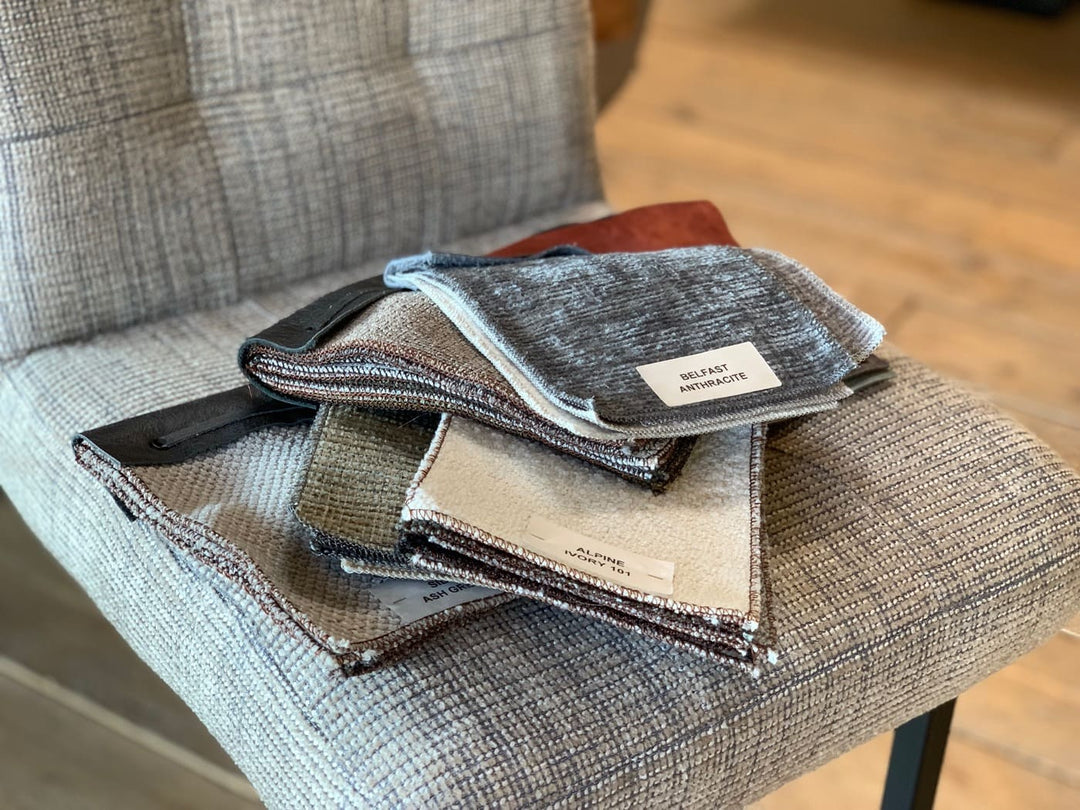 Barhocker Stoffbezug Industrial Stoffauswahl: Detailaufnahme von verschiedenen Stoffmustern in Grau- und Beigetönen auf der Sitzfläche eines Barhockers, die die Auswahl an hochwertigen Stoffbezügen im Industrial-Stil zeigt.