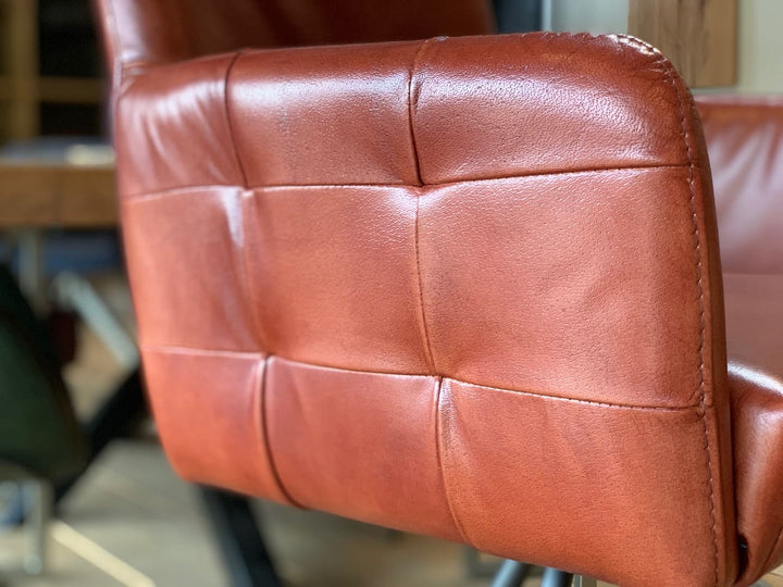 Barstuhl drehbar Leder Industrial Detail: Nahaufnahme der gepolsterten Rückenlehne aus rotem Leder mit markanter Steppung und feiner Struktur, die die hochwertige Verarbeitung im Industrial-Stil hervorhebt.