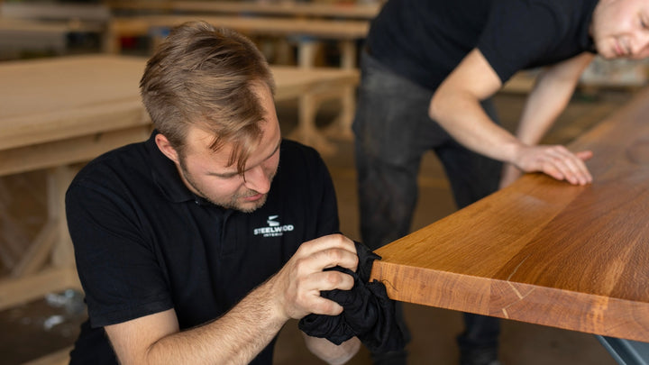 Bild von zwei Mitarbeitern von Steelwood Interior die einen Massivholztisch ölen