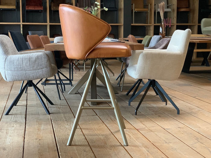 Design Barhocker Leder in Seitenansicht, drehbarer Barstuhl mit eleganter Sitzschale und Armlehnen, hochwertiger Lederbezug in Cognac und stabiles Metallgestell mit Sternfuß, ideal für moderne Wohn- und Barbereiche.