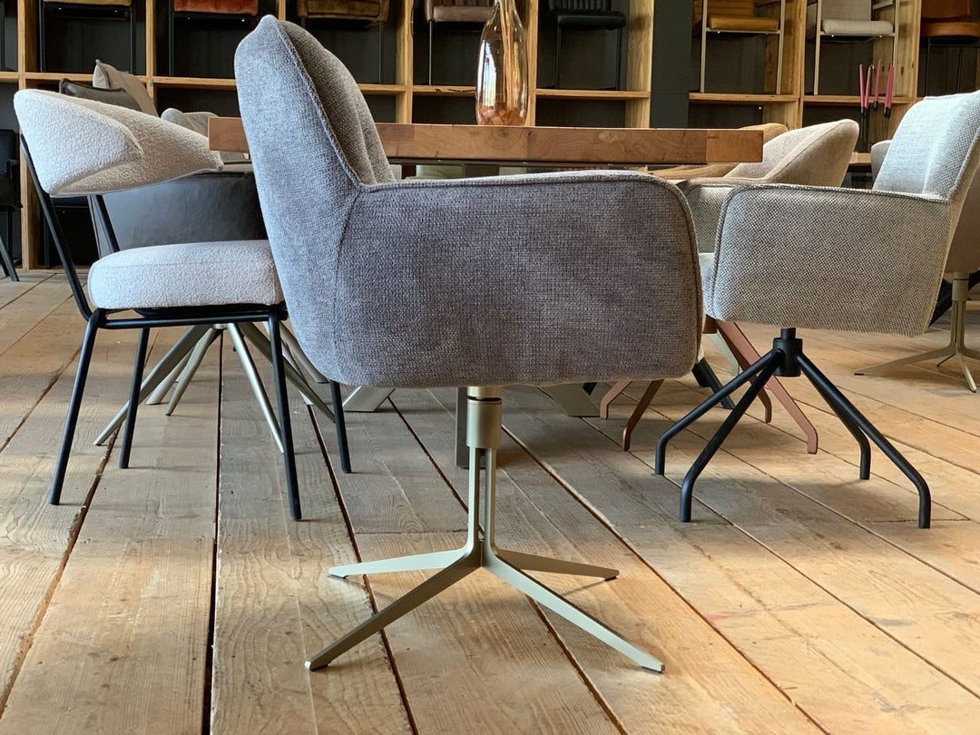 Designer Esszimmer-Drehstuhl in Seitenansicht, grauer Stoffbezug mit Armlehnen und drehbares Metallgestell in modernem Wohnambiente.