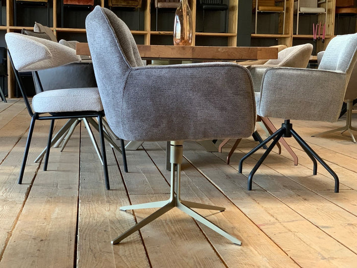 Designer Esszimmer-Drehstuhl in Seitenansicht, grauer Stoffbezug mit Armlehnen und drehbares Metallgestell in modernem Wohnambiente.