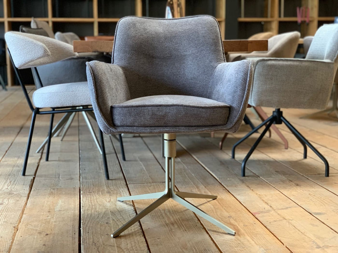 Designer Esszimmer-Drehstuhl in Vorderansicht, grauer Stoffbezug mit Armlehnen, gepolsterte Sitzfläche und elegantes drehbares Metallgestell.