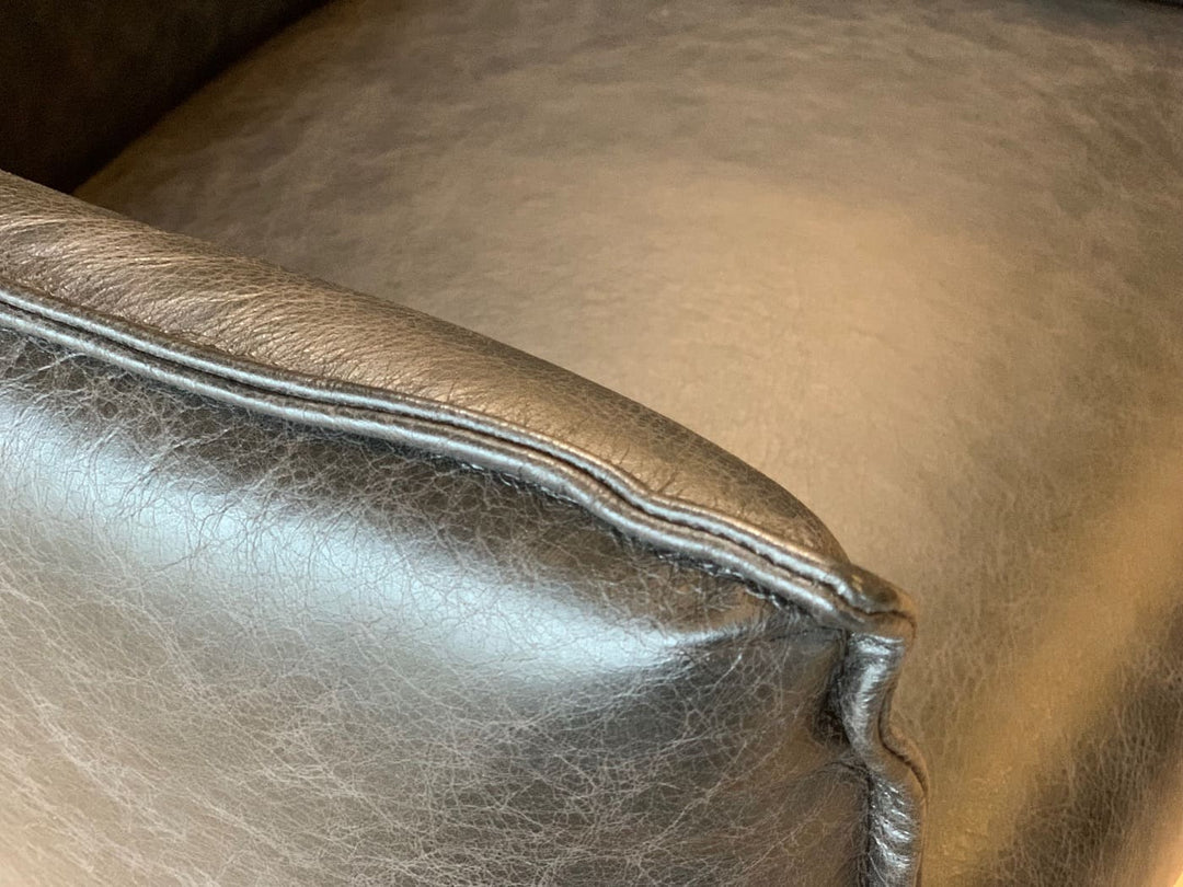 Detailansicht eines Lederstuhls mit sichtbarer Nahtführung und hochwertiger schwarzer Lederoberfläche, die Struktur und Verarbeitung des Materials zeigt.