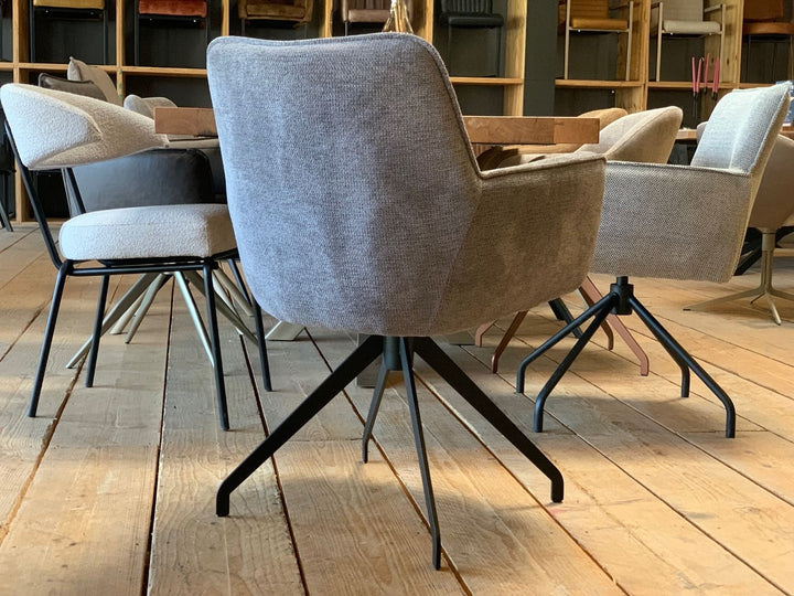 Drehbarer Essstuhl mit grauem Stoffbezug in Rückansicht, gepolsterter Rückenlehne und schwarzem Metall-Drehgestell im modernen Esszimmer.