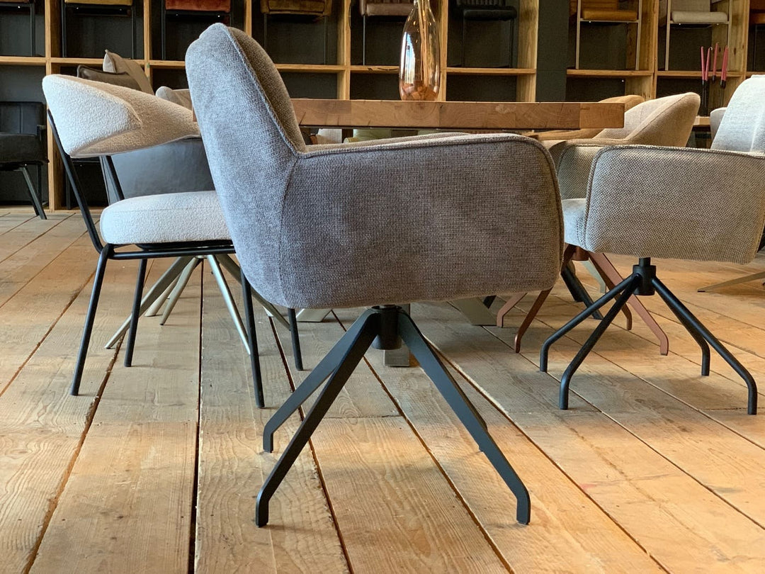 Drehbarer Essstuhl mit grauem Stoffbezug in Seitenansicht, gepolsterter Sitz und schwarzem Metall-Drehgestell in modernem Esszimmer.