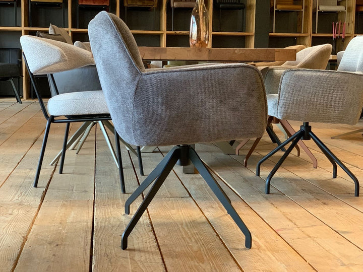 Drehbarer Essstuhl mit grauem Stoffbezug in Seitenansicht, gepolsterter Sitz und schwarzem Metall-Drehgestell in modernem Esszimmer.