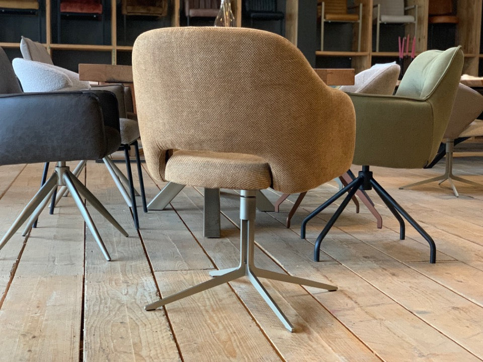 Drehbarer Armlehnenstuhl in eleganter Rückansicht mit hochwertigem Stoffbezug in warmem Beige. Die weich gepolsterte Rückenlehne überzeugt durch ihre klare, moderne Form und angenehme Haptik. Das stabile Metallgestell in hellem Finish sorgt für sicheren Stand und ergänzt das Design mit einer leichten, zeitgemäßen Optik – ideal für stilvolle Essbereiche und Wohnräume.