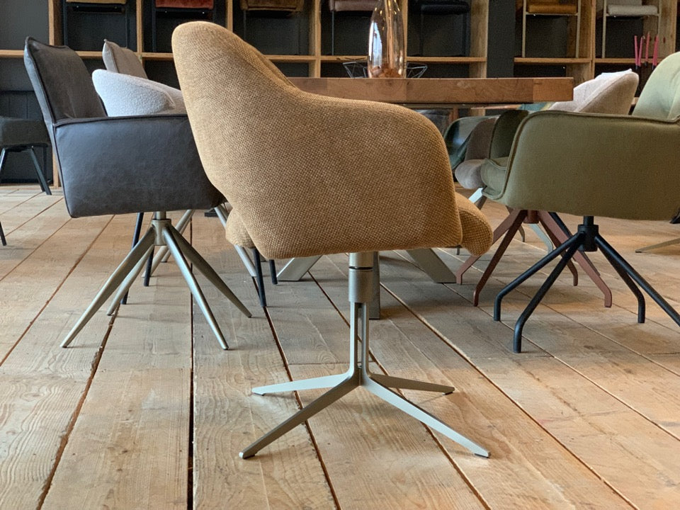 Drehbarer Armlehnenstuhl in moderner Seitenansicht mit hochwertigem Stoffbezug in warmem Beige. Die ergonomisch geformte Sitzschale mit sanft geschwungener Rückenlehne und integrierten Armlehnen bietet hohen Sitzkomfort. Das elegante Metallgestell in hellem Finish sorgt für Stabilität und verleiht dem Stuhl eine leichte, zeitgemäße Optik – ideal für stilvolle Essbereiche.