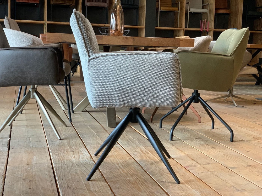 Drehbarer Polsterstuhl in Seitenansicht mit gepolstertem Stoffbezug und schwarzem Metall-Drehgestell im modernen Esszimmer