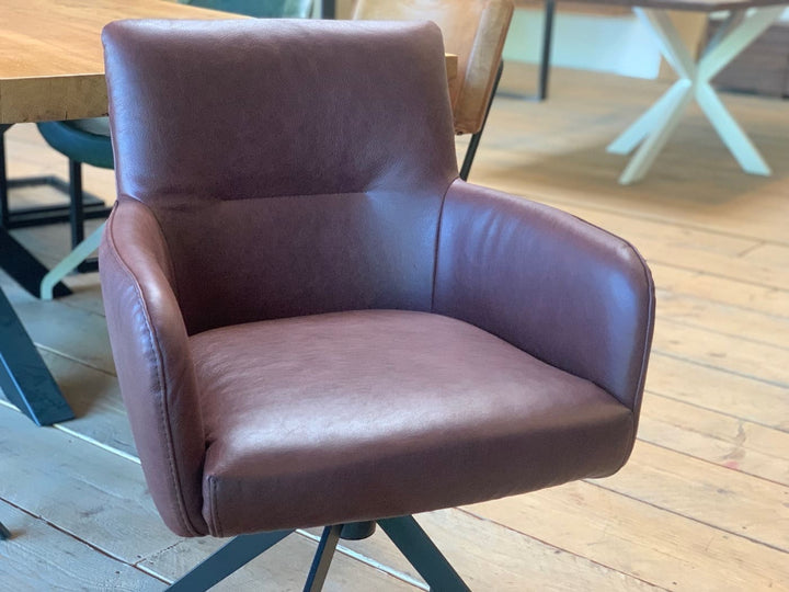 Detailaufnahme eines drehbaren Drehstuhls aus Echtleder mit weich gepolsterter Sitzfläche, geschwungenen Armlehnen und ergonomischer Rückenlehne in hochwertiger Lederoptik.