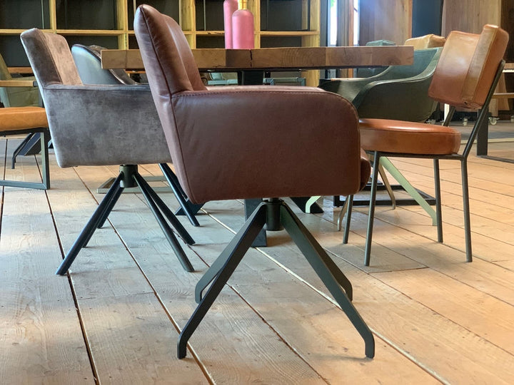 Seitenansicht eines drehbaren Drehstuhls aus Echtleder mit gepolsterter Sitzfläche, bequemen Armlehnen und stabilem Metallgestell in modernem Esszimmer.