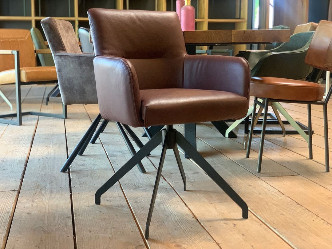 Moderner Drehstuhl aus Echtleder mit gepolsterter Sitzschale, integrierten Armlehnen und stabilem Metallgestell in stilvollem Esszimmer-Ambiente.