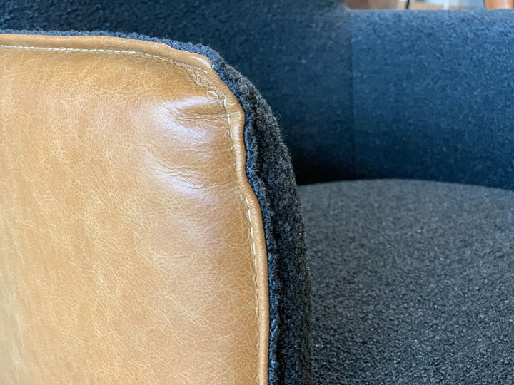 Detailaufnahme eines Esszimmer Drehstuhls mit Leder-Stoff Kombination, braunes Leder mit sichtbarer Naht und Übergang zu schwarzem Stoffbezug