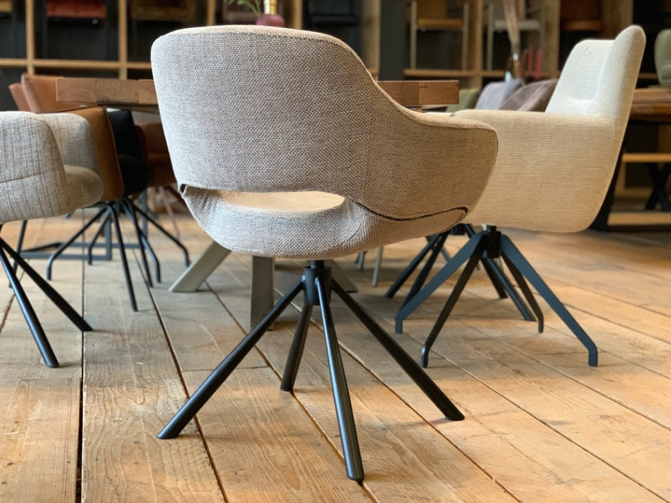 Seitenansicht eines modernen Esszimmer Drehstuhls mit beigem Stoffbezug und schwarzem Metallgestell, ergonomischer Schalenstuhl