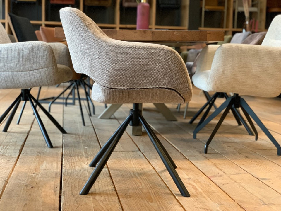 Seitenansicht eines modernen Esszimmer Drehstuhls mit beigem Stoffbezug und schwarzem Metallgestell, ergonomischer Schalenstuhl