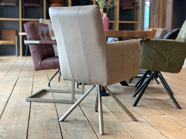 Rückansicht eines modernen Drehstuhl Leder hohe Rückenlehne in hochwertigem Leder in der Farbe Taupe, mit klarer Linienführung und gepolsterter Sitzfläche auf einem stabilen Metall-Drehgestell, platziert an einem Holztisch in einem stilvollen Essbereich.