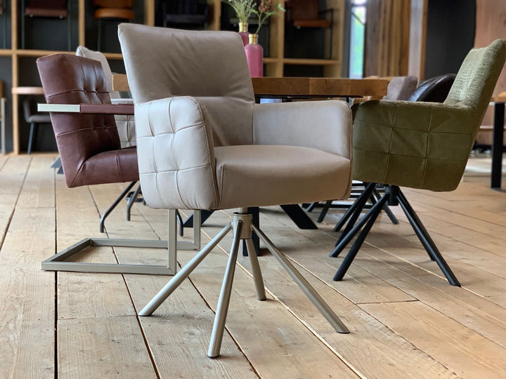 Moderner Drehstuhl Leder hohe Rückenlehne in hochwertigem Leder in der Farbe Taupe, mit gepolsterter Sitzfläche und Armlehnen auf einem stabilen Metall-Drehgestell, kombiniert mit weiteren Esszimmerstühlen an einem Holztisch in einem stilvollen Ambiente.