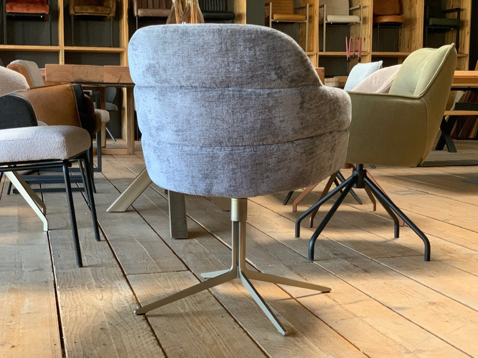 Rückansicht eines drehbaren Polsterstuhls mit grauem Stoffbezug und modernem Metallgestell in Goldoptik in einem stilvollen Esszimmer.