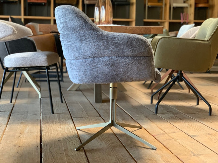 Seitenansicht eines drehbaren Polsterstuhls mit Armlehnen, grauem Stoffbezug und modernem Metallgestell in Silberoptik im Esszimmer.