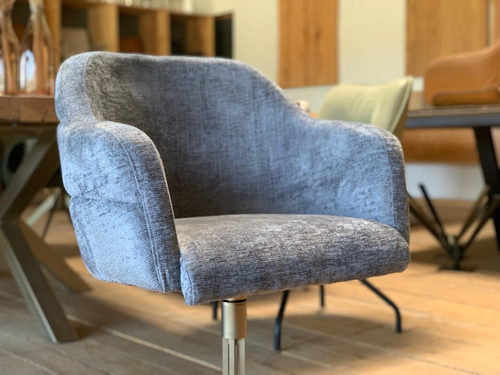 Detailaufnahme der gepolsterten Sitzschale eines drehbaren Polsterstuhls mit grauem Stoffbezug in modernem Esszimmerambiente.