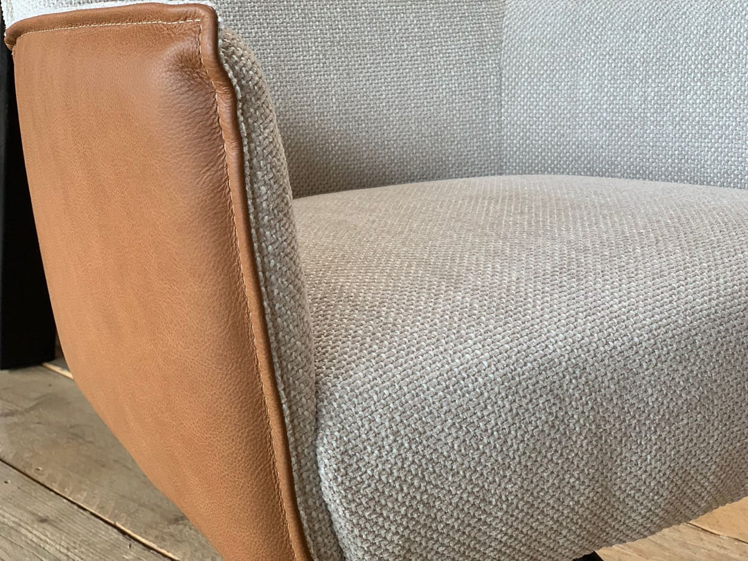 Detailaufnahme eines Esszimmer Drehstuhls mit Kombination aus Leder und Stoff, sichtbarer Übergang zwischen braunem Leder und strukturiertem Textilbezug am Sitz