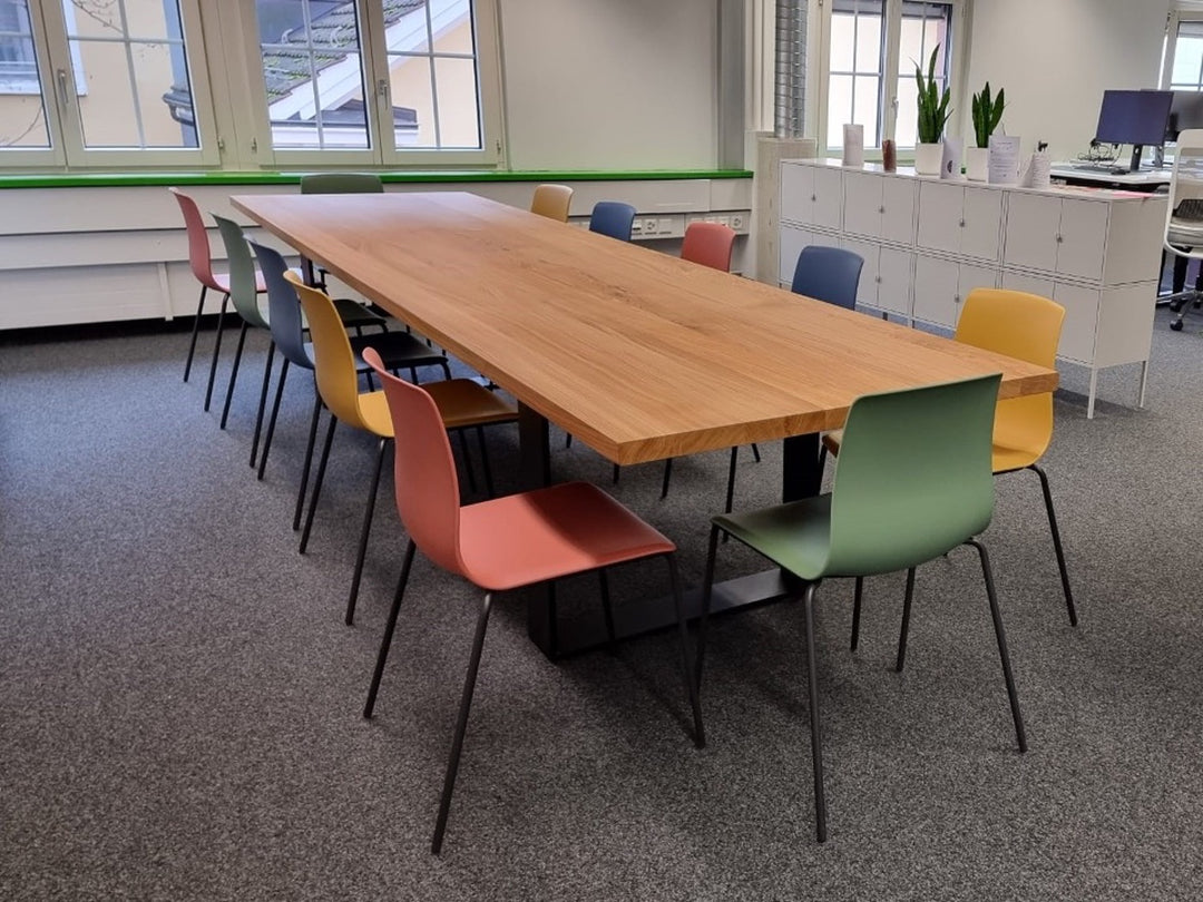 Kundenfoto aus einem Büro mit vielen bunten Stühlen und dem Esstisch aus Eiche Nora mit Tischkufen 