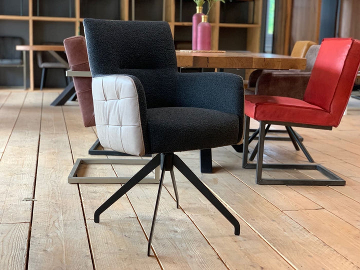 Esszimmer Drehstuhl Leder Stoff: Moderner Drehstuhl mit schwarzem Stoffbezug und hellen Leder-Armlehnen auf Metallgestell, kombiniert mit farbigen Esszimmerstühlen an einem Holztisch in stilvollem Wohnambiente.