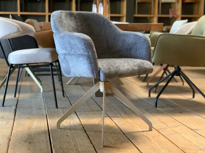 Moderner Esszimmer-Drehstuhl mit Stoffbezug – stilvolle Sitzschale mit weicher Polsterung, ergonomischen Armlehnen und elegantem Metallgestell in heller Ausführung für ein modernes Wohnambiente.