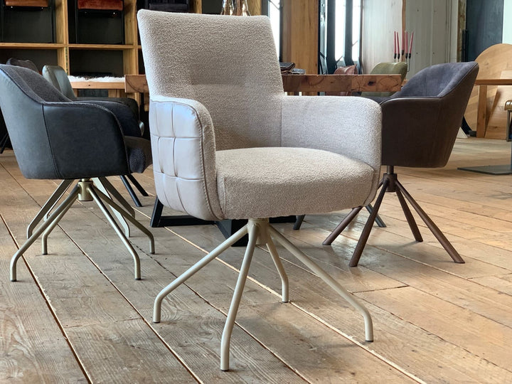 Esszimmer Drehstuhl hohe Rückenlehne: Moderner Drehstuhl mit hoher Rückenlehne, weichem Stoffbezug und seitlichen Lederdetails, auf stabilem Metallgestell, kombiniert mit stilvollen Esszimmerstühlen an einem Holztisch.