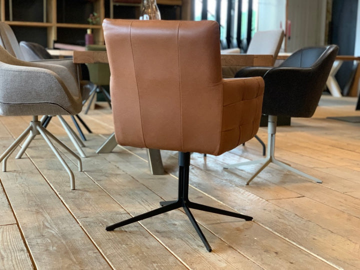 Rückseite Esszimmer Lederstuhl drehbar aus hochwertigem braunem Leder mit gepolsterter Sitzfläche, Armlehnen und schwarzem Sternfuß in einem modernen Esszimmer.