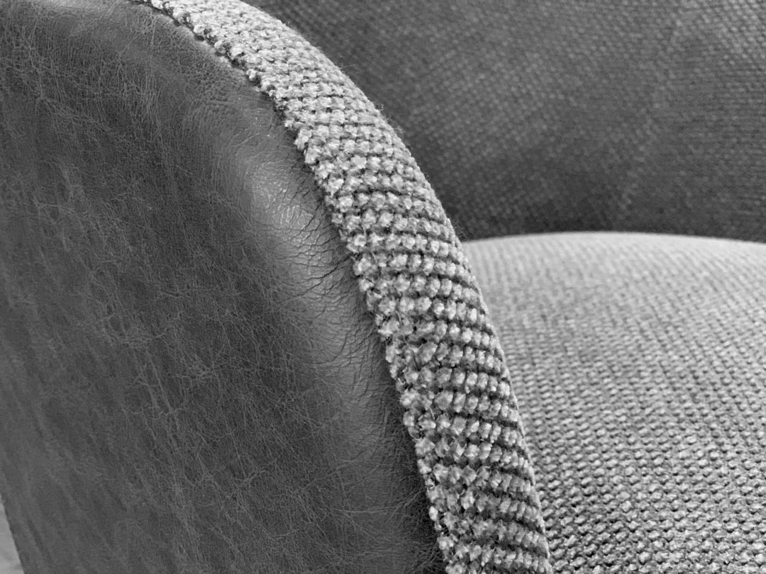 Detailaufnahme eines Esszimmerstuhls mit Kombination aus grauem Stoffbezug und Lederseite, sichtbare Naht und hochwertige Materialstruktur