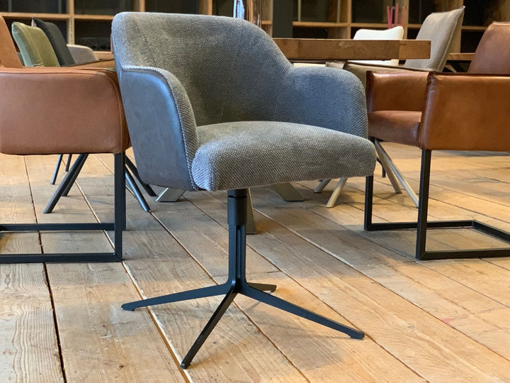 Esszimmerstuhl Kombination Stoff Leder drehbar in moderner Optik mit grauem Stoffbezug, seitlichen Lederflächen und schwarzem Metall-Drehgestell, stilvoll platziert an einem Esstisch auf Holzboden