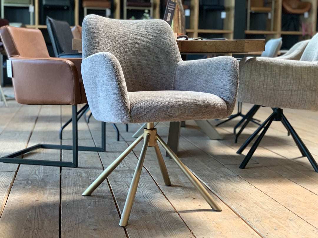 Moderner Esszimmerstuhl mit Stoffbezug und drehbarem Stahlgestell in eleganter Optik. Die weich gepolsterte Sitzschale mit integrierten Armlehnen sorgt für hohen Sitzkomfort, während das stabile, filigrane Metallgestell in warmem Finish dem Stuhl eine stilvolle und zeitgemäße Ausstrahlung verleiht – perfekt für moderne Ess- und Wohnbereiche.