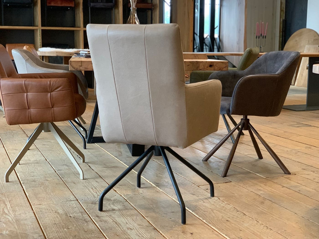 Esszimmerstuhl drehbar aus Leder in Taupe mit Armlehnen in Rückansicht, an einem Holztisch in moderner Wohnumgebung mit weiteren gepolsterten Stühlen auf hellem Holzboden.