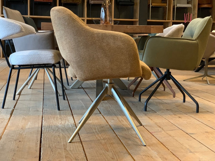Moderner Esszimmerstuhl mit Drehfunktion und hochwertigem Stoffbezug in warmem Beige. Die komfortabel gepolsterte Sitzschale mit integrierten Armlehnen sorgt für angenehmes Sitzen, während das elegante Metallgestell in hellem Finish dem Stuhl eine stilvolle, zeitgemäße Optik verleiht – ideal für ein modernes Esszimmer.