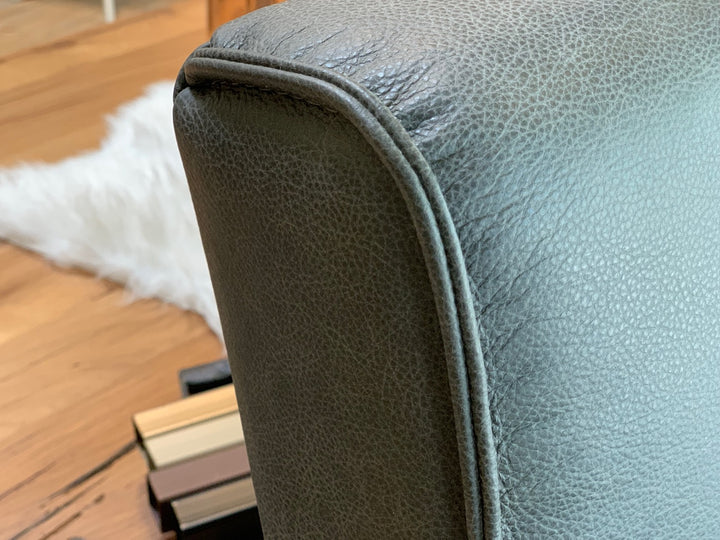 Detailaufnahme einer Hochbank aus Leder mit grauem Bezug, sichtbarer Naht und feiner Lederstruktur an der Rückenlehne im modernen Design.