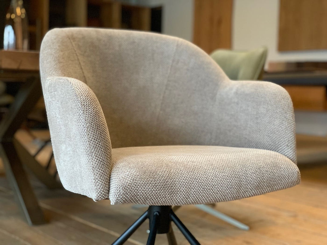 Detailaufnahme der Sitzschale eines hochwertigen, drehbaren Armlehnenstuhls mit ergonomisch geschwungener Form, bezogen mit fein strukturiertem Stoff in elegantem Beigeton – für maximalen Sitzkomfort und modernes Design im Essbereich.