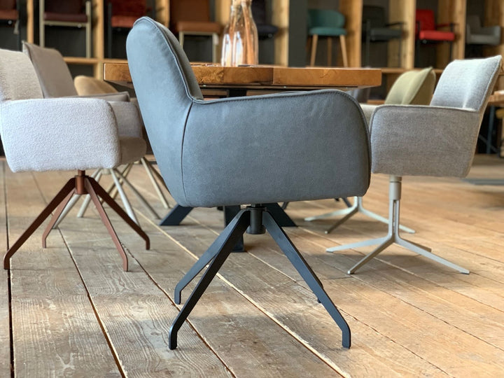 Seitenansicht eines hochwertigen Drehstuhls aus Leder mit Armlehnen und modernem Metallgestell, stilvoll inszeniert in einem eleganten Showroom.