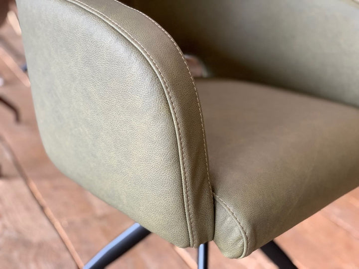 Detailaufnahme eines drehbaren Leder Armlehnstuhls in Grün, mit Fokus auf die hochwertige Lederstruktur, präzise Nahtführung und die sorgfältige Verarbeitung der Polsterkante.