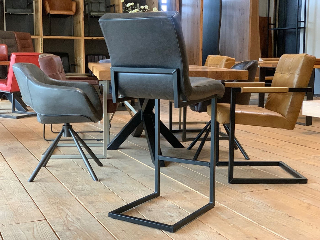 Leder Barhocker schwarz in Rückansicht mit hoher Rückenlehne und stabilem Metallgestell, positioniert an einem Holztisch im modernen Essbereich.