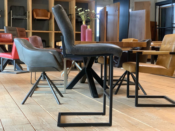 Barhocker Leder schwarz in Seitenansicht mit gepolsterter Sitzfläche und schlankem Metallgestell, im modernen Essbereich mit Holztisch und Designerstühlen.
