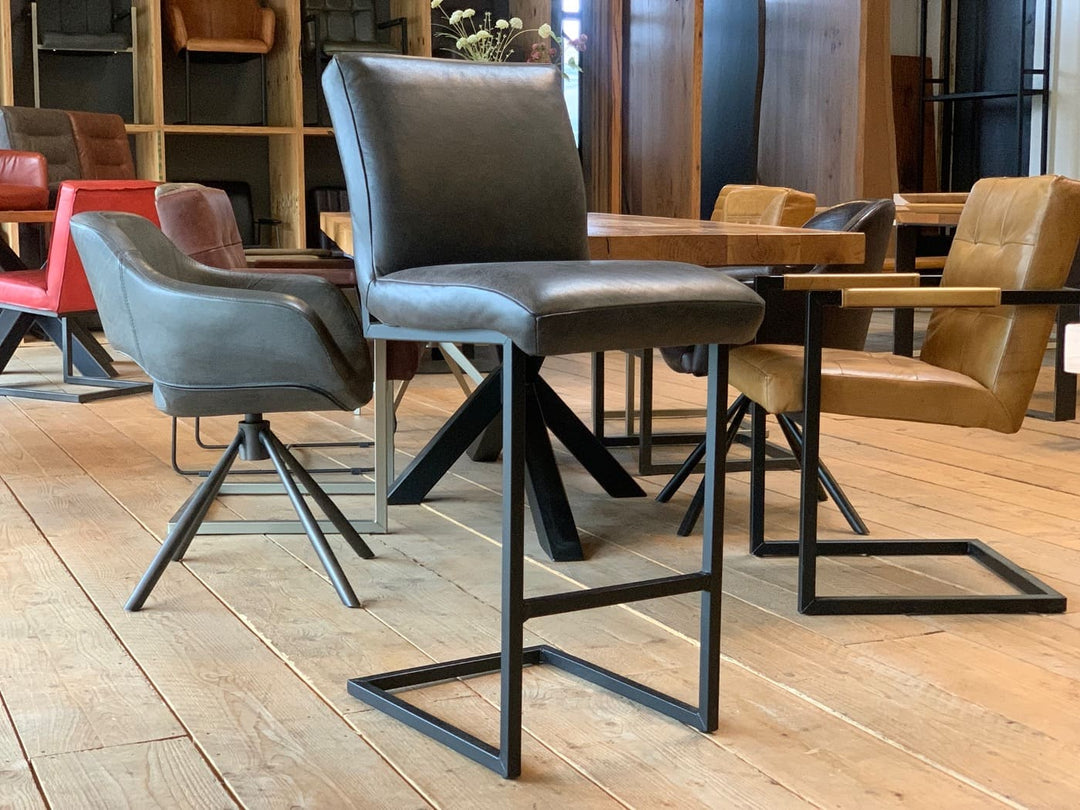 Barhocker Leder in Schwarz mit gepolsterter Sitzfläche und modernem Kufengestell aus Metall, im stilvollen Essbereich mit Holztisch und weiteren Stühlen.