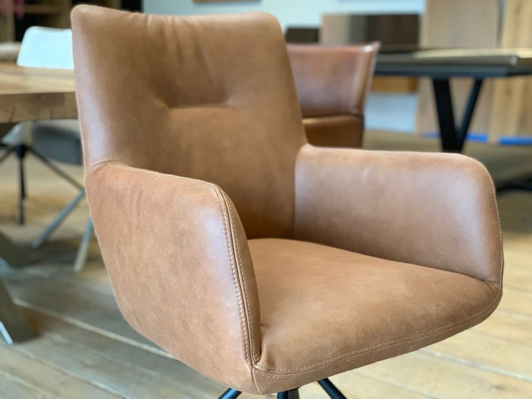 Detailaufnahme eines Leder Esszimmer Drehstuhl in Cognac mit weich gepolsterter Sitzschale, Armlehnen und feiner Nahtführung, die die hochwertige Verarbeitung und den Komfort des Stuhls hervorhebt.