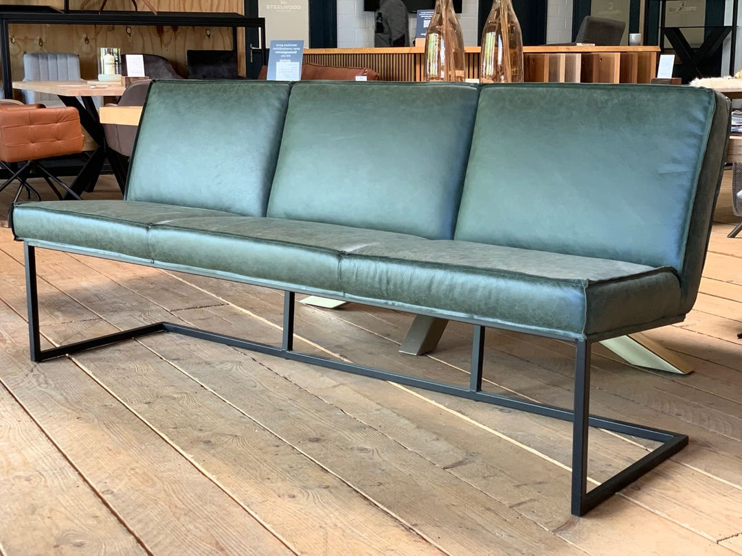 Moderne Sitzbank mit grünem Lederbezug und schwarzem Metallgestell in einem stilvollen Möbel-Showroom auf Holzboden