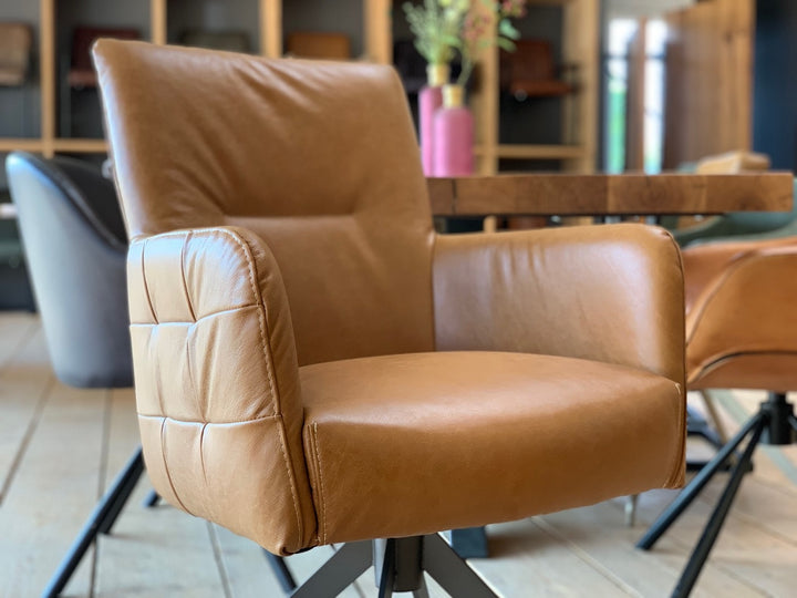 Detailaufnahme eines Lederstuhl hohe Rückenlehne drehbar in Cognac mit weicher Polsterung, sichtbaren Nähten und hochwertigem Lederbezug an Sitzfläche und Armlehne, im modernen Esszimmerambiente.