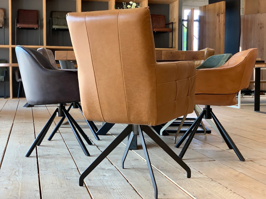 Rückansicht eines eleganten Lederstuhl hohe Rückenlehne drehbar in Cognac mit glatter Rückenfläche und hochwertigem Lederbezug, ausgestattet mit stabilem schwarzem Metall-Drehgestell, im modernen Esszimmer mit Holztisch und weiteren Lederstühlen.