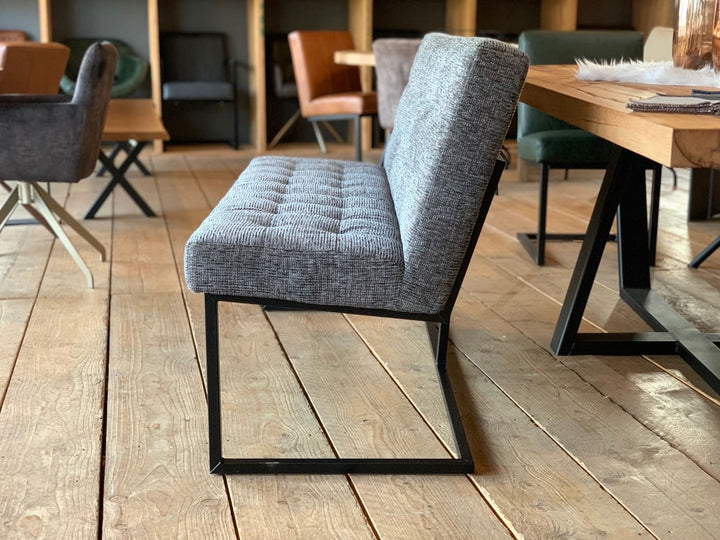 Moderne Sitzbank aus grauem Stoff mit gepolsterter Sitzfläche und schwarzem Metallgestell, Seitenansicht im stilvollen Esszimmer neben Holztisch
